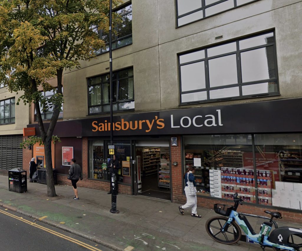 A calm thief steals 4 wine bottles from Sainsbury’s in Finsbury Park, ignoring staff and cameras. Locals outraged as shoplifting rises amid the cost-of-living crisis.