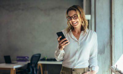 businesswoman smiles holding mobile phone office