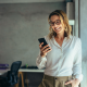 businesswoman smiles holding mobile phone office