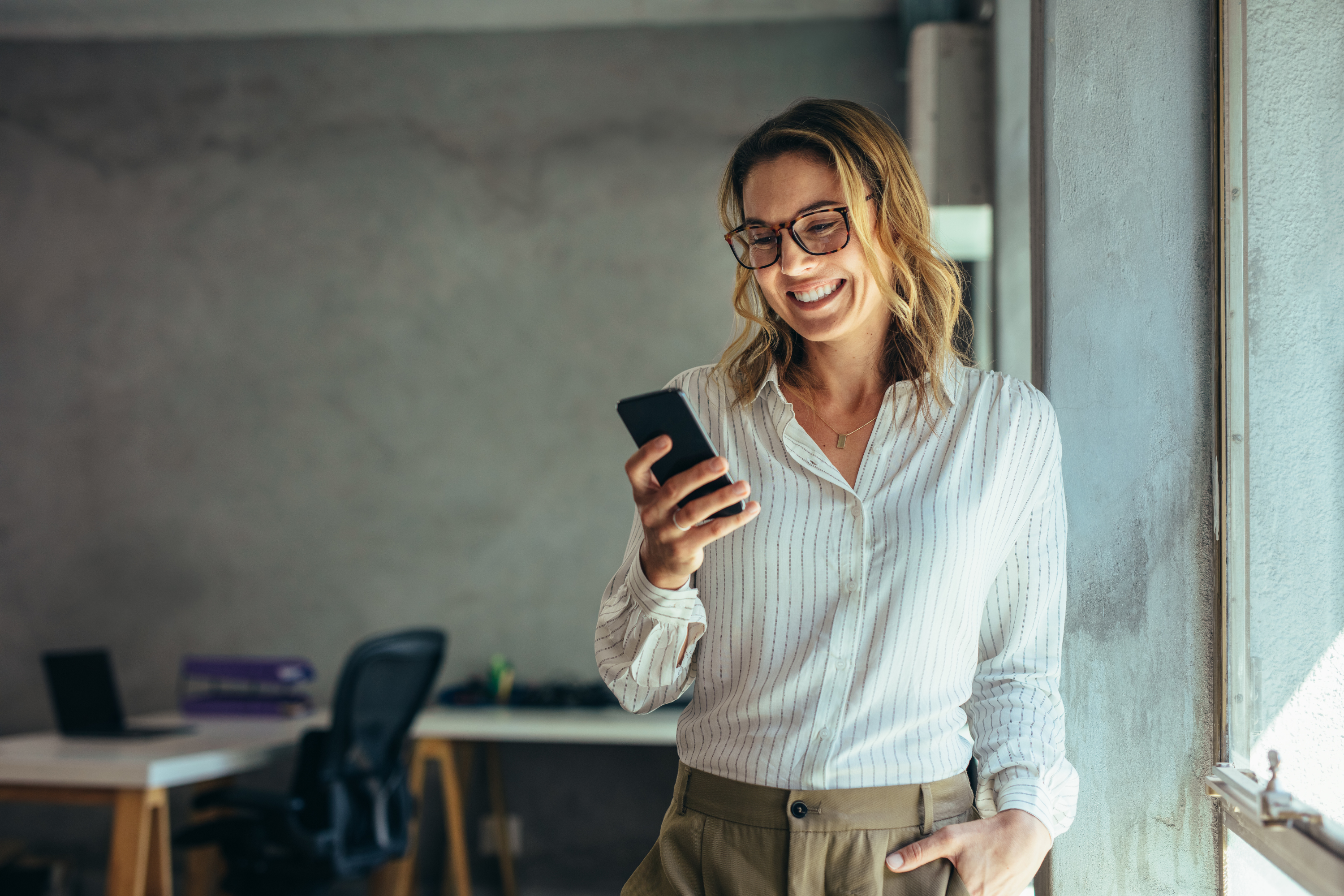 businesswoman smiles holding mobile phone office