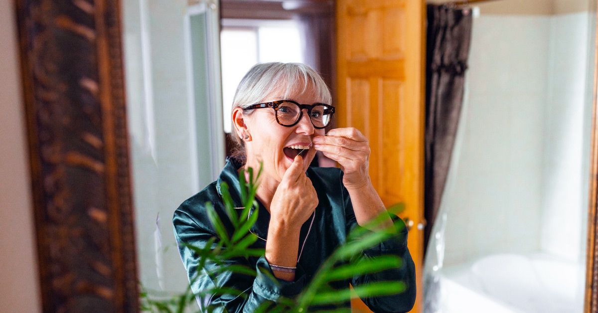 female flossing teeth 1200x628 facebook