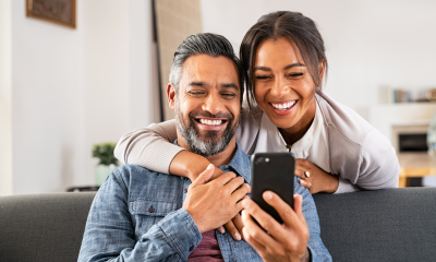 happy couple home smiles viewing mobile phone