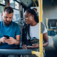 man woman ride bus using mobile phones