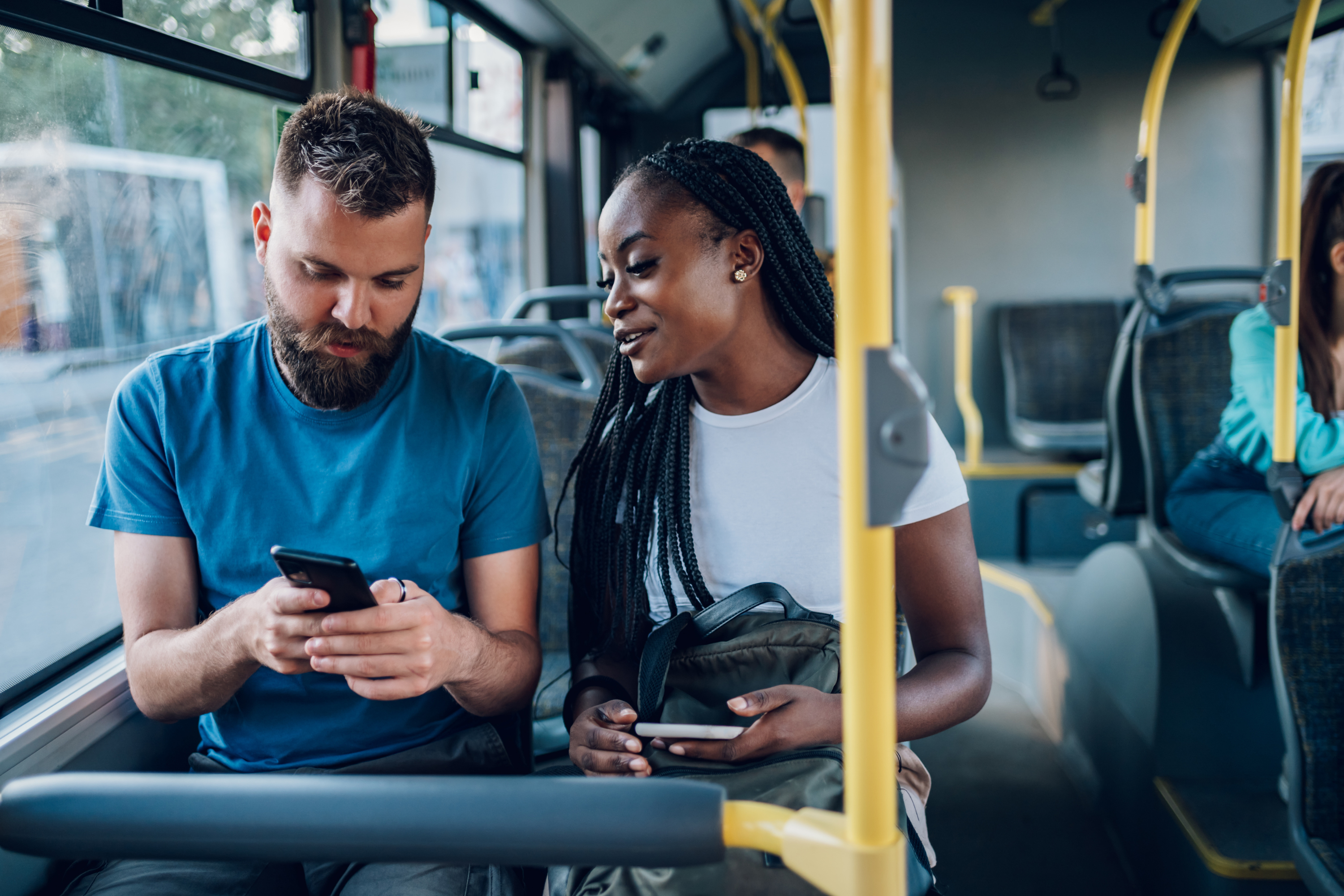 man woman ride bus using mobile phones