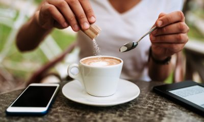 person putting sugar in coffee