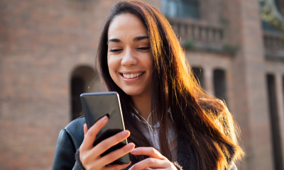 woman long hair smiles mobile phone street