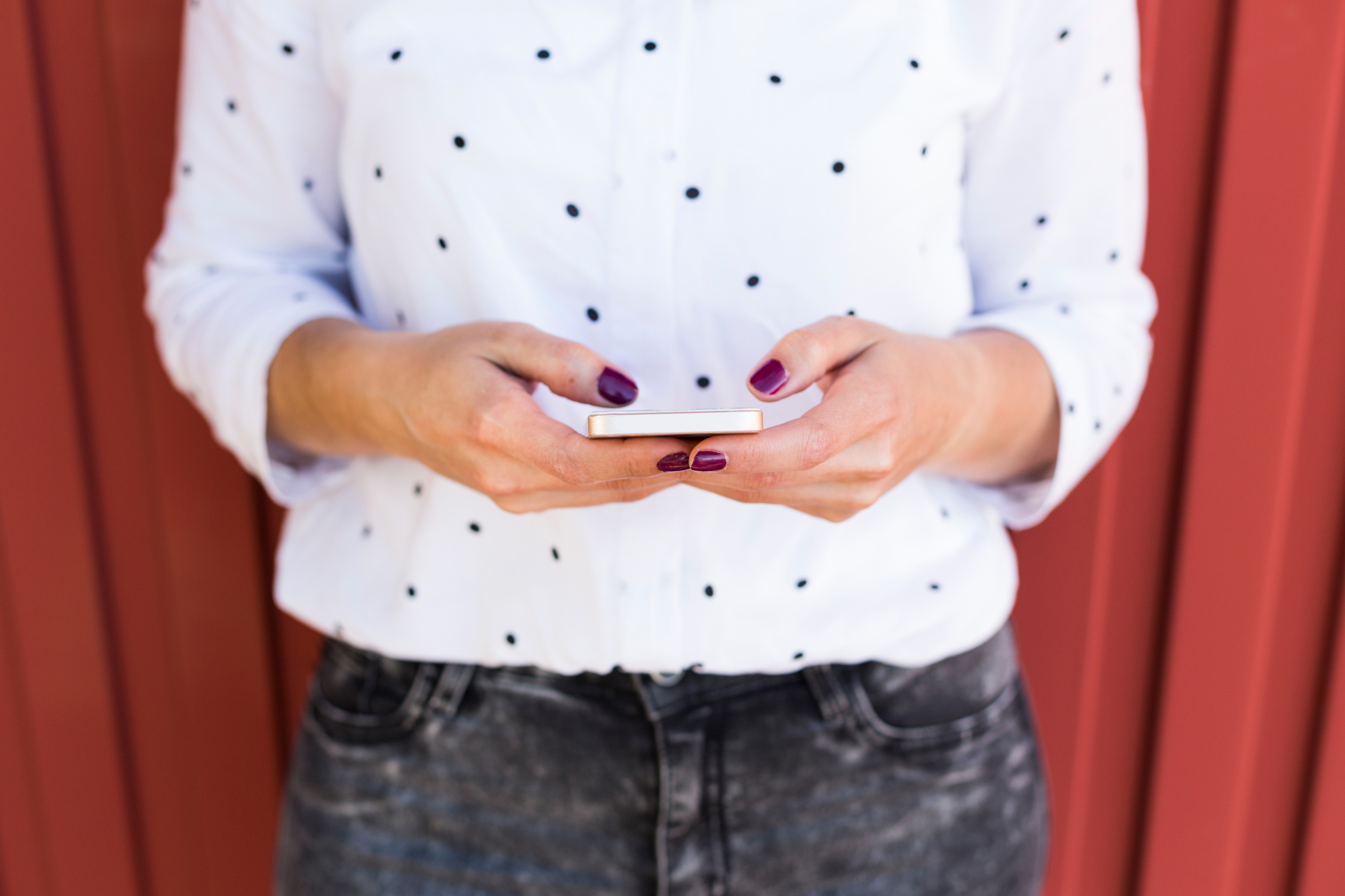 woman painted nails polka dot shirt phone