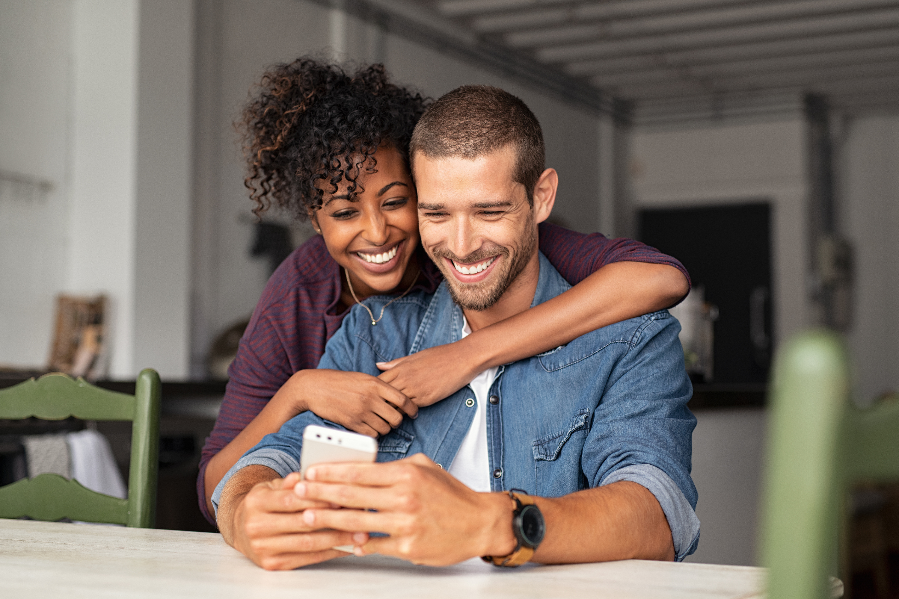 happy couple embrace dining table mobile phone