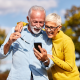 happy older couple smiles mobile phone outdoors