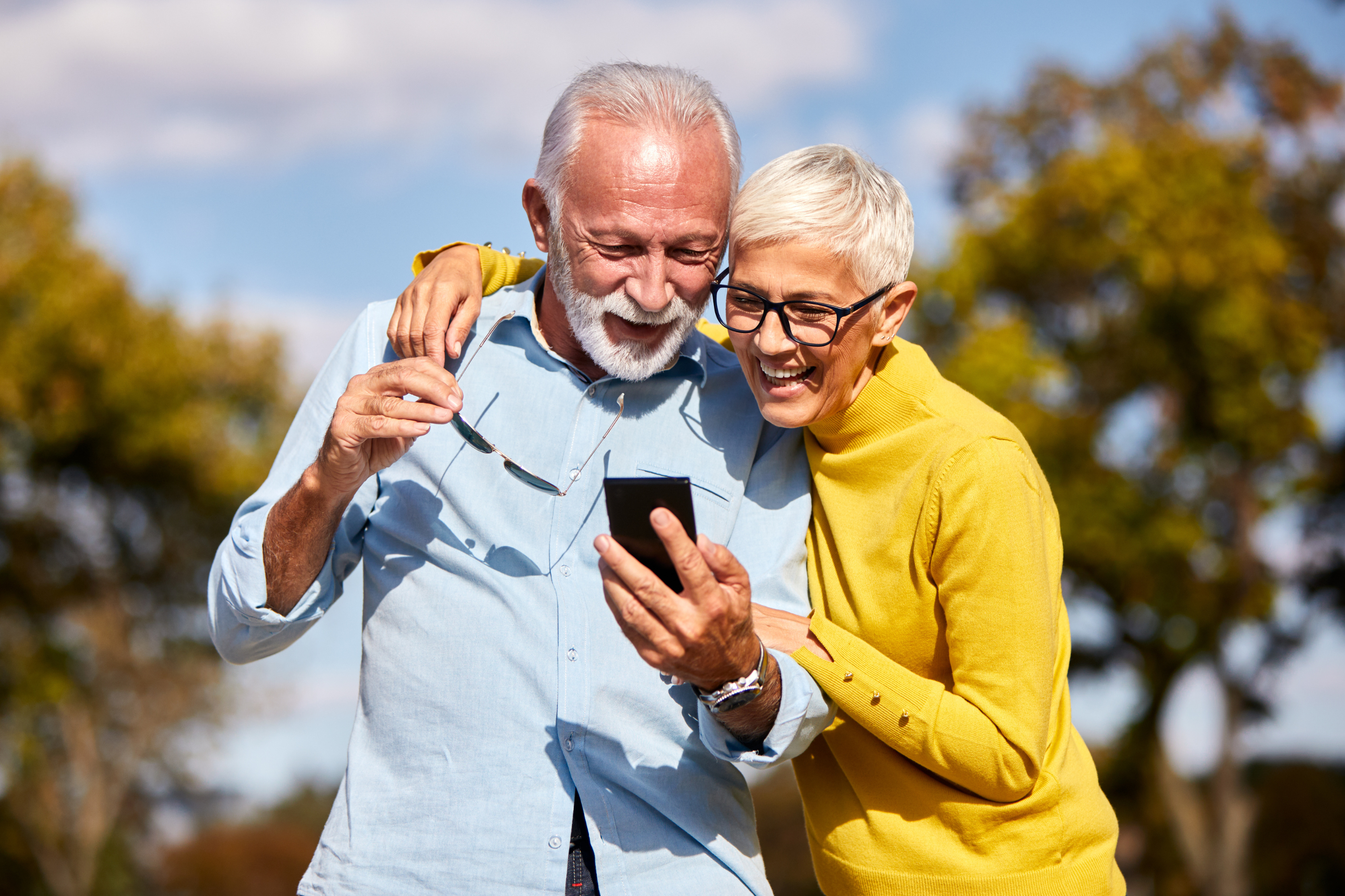 happy older couple smiles mobile phone outdoors