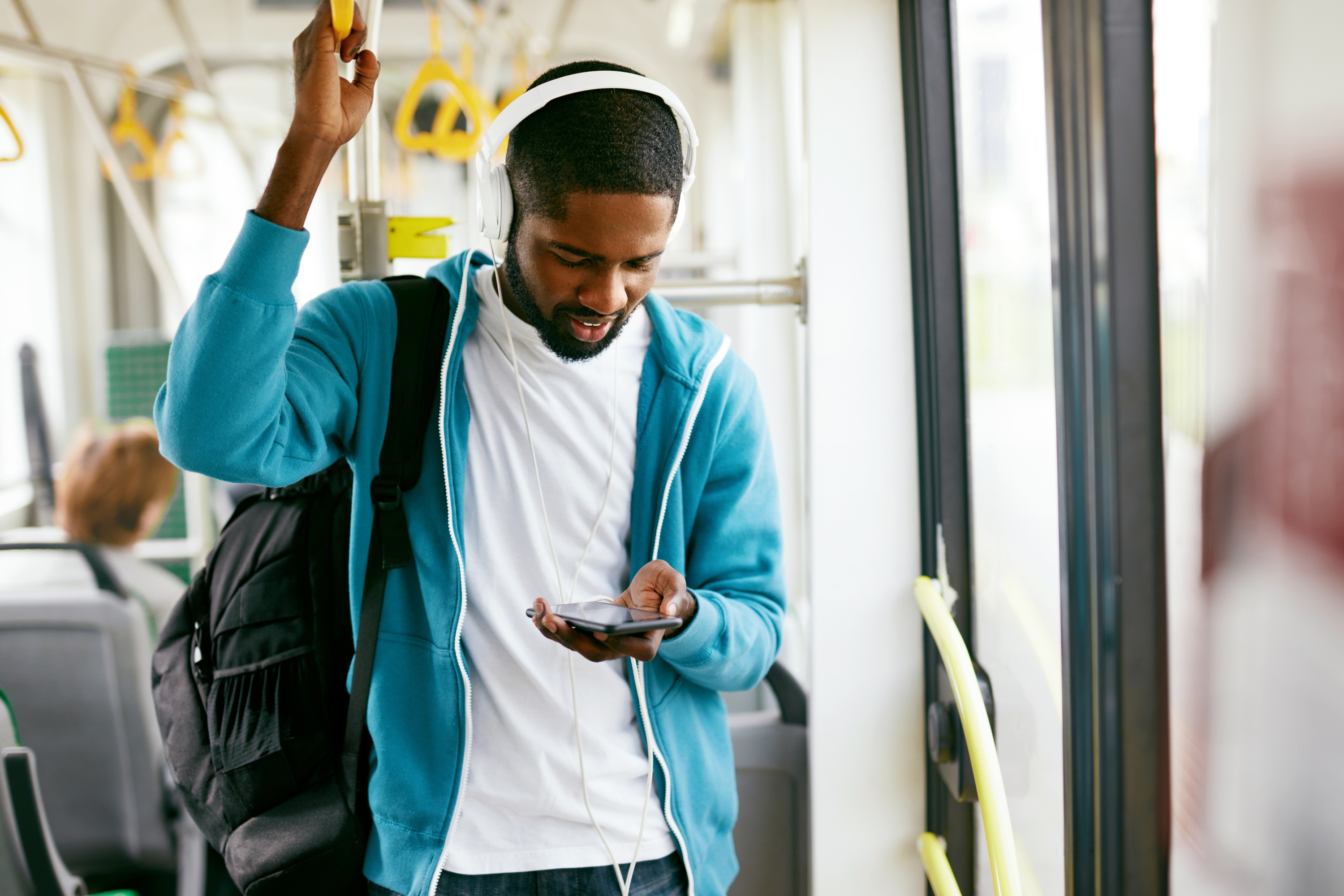 man backpack blue sweatshirt listens music train