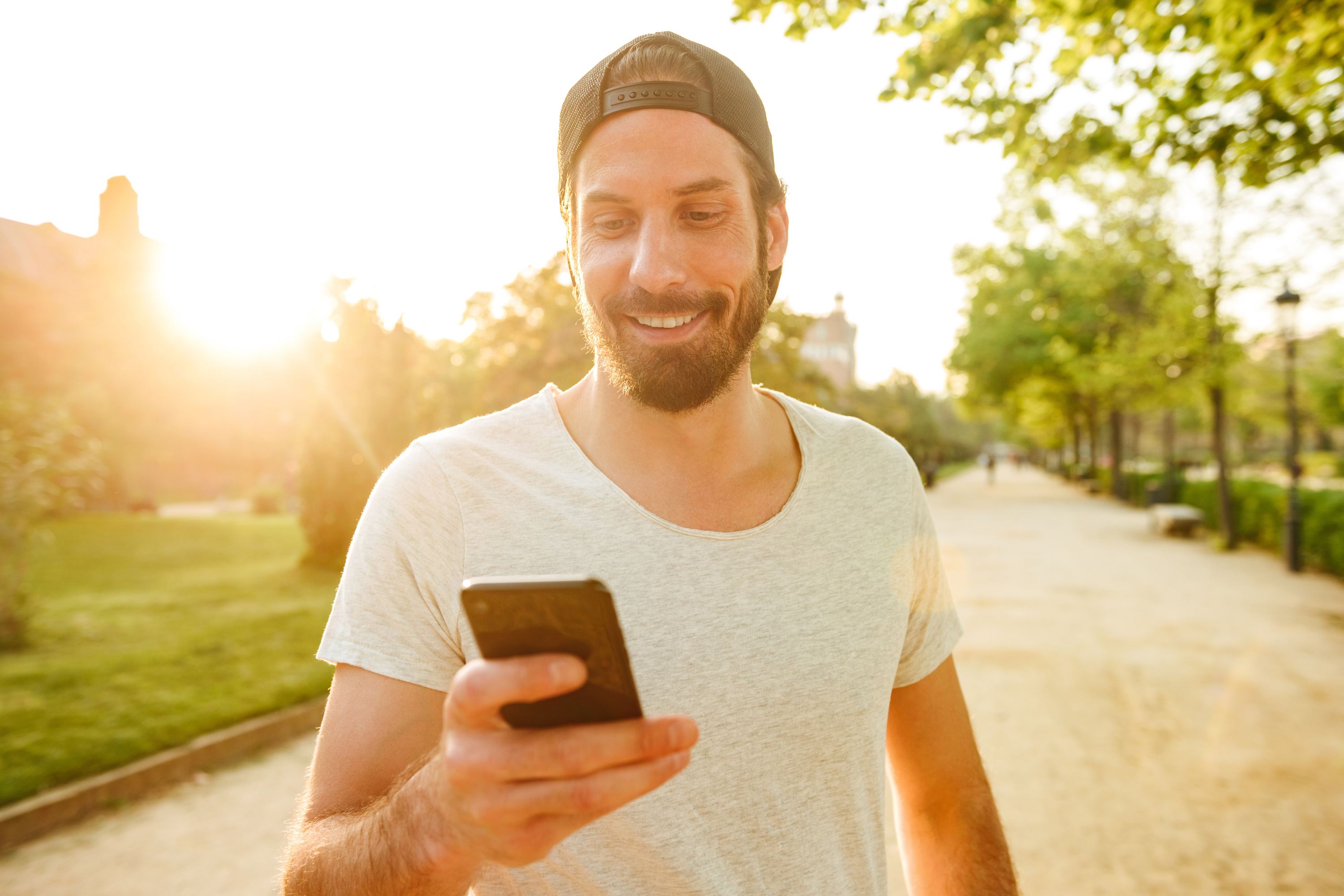 man t shirt backward hat park mobile phone