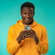 man yellow sweatshirt mint green background phone