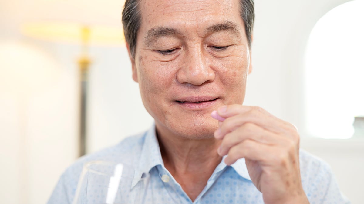 older adult taking vitamin with water