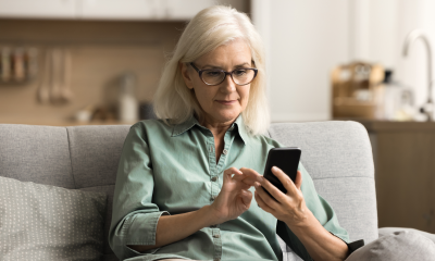 older woman sits couch mobile phone home