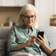 older woman sits couch mobile phone home