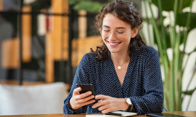 woman glasses sits desk mobile phone office