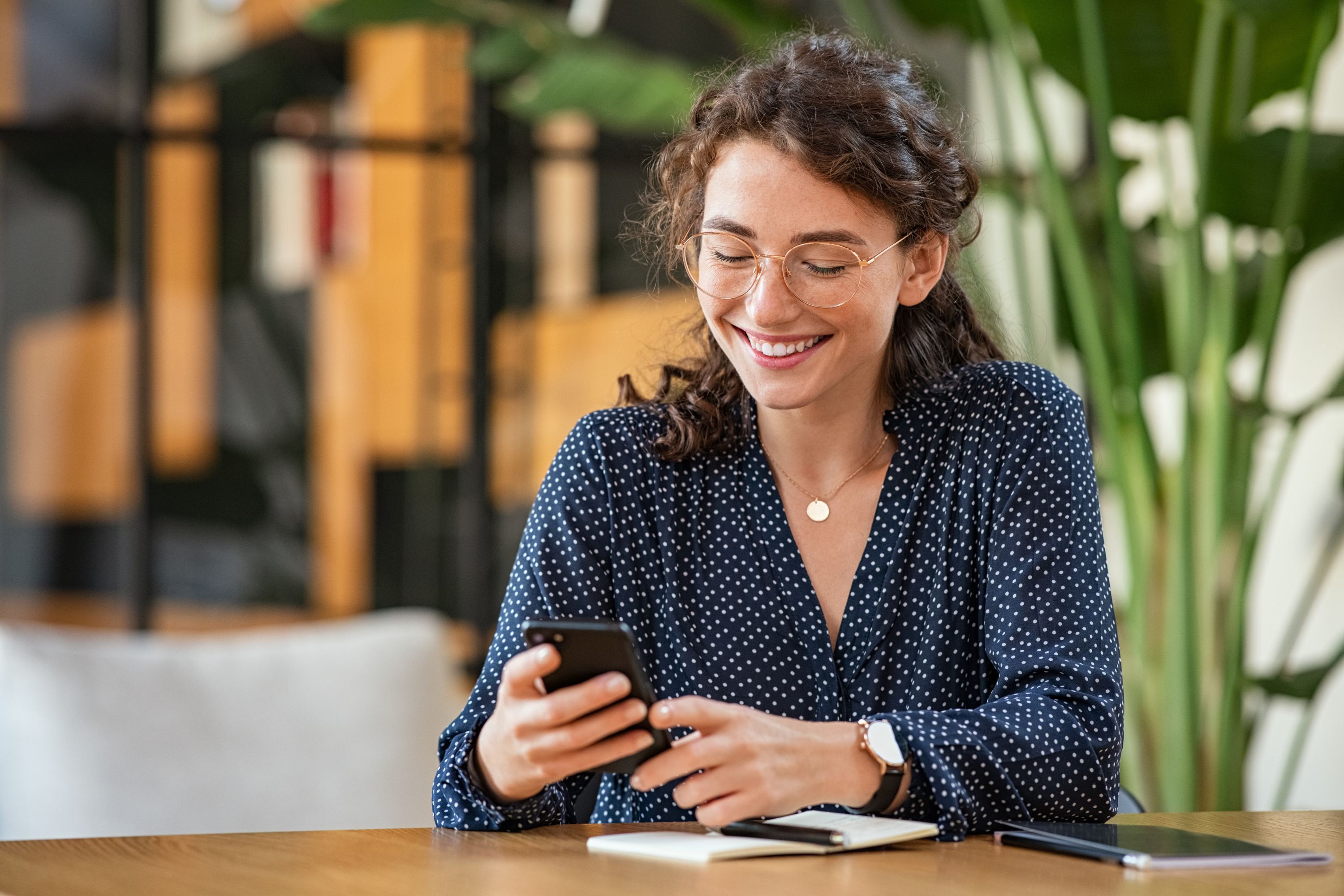 woman glasses sits desk mobile phone office